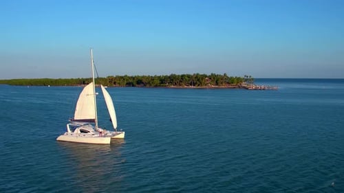 Turquoise waters surround a catamaran sailing near a tropical island in the bahamas