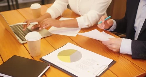 Business Partners Analyse Papers for Project at Cafe Table