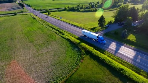 Aerial shot of a blue cargo truck on a country road.