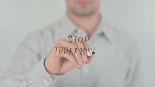 Man Writes 'Stop Trafficking' on Glass Surface