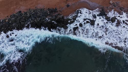 Waves Crashing on Rocky Shoreline: Aerial Beach Scenery
