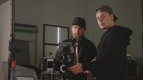 Two Cameramen Setting up Video Camera for Shooting in Studio