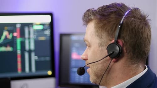 Mittlere Aufnahme eines chattenden Mannes mit technischem Support und einem Headset in einem Handelsmaklerbüro