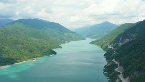 Stunning aerial panoramic view of mountain valley turquoise lake surrounded by green lush forest and
