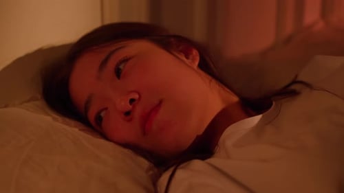 Woman Lying on Pillow in Warm Bedroom Light