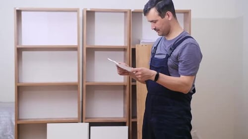 Man Assembling Furniture Indoors Using Instructions