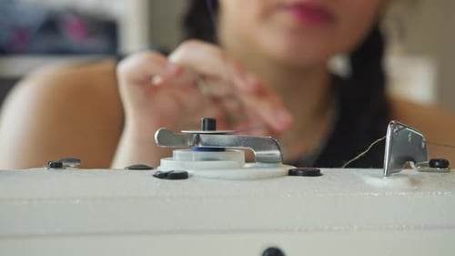 A costureira controla cuidadosamente a distribuição uniforme da linha azul em bobinas rotativas de costura