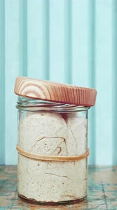 Sourdough Starter Growing in Glass Jar with Wooden Lid