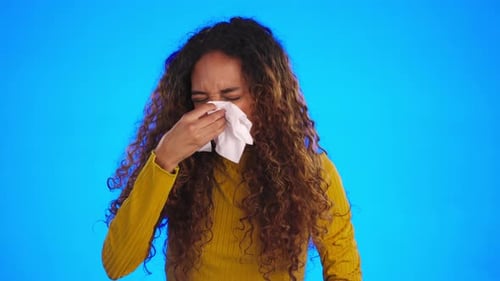 Woman Sneezing with Tissue on Blue Background