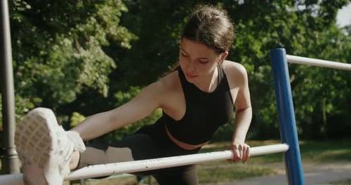 Woman Stretching on Horizontal Bars in Park
