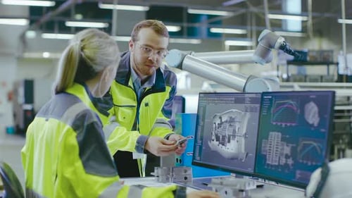 At the Factory: Male Mechanical Engineer Holds Component and Female Chief Engineer Work on Personal
