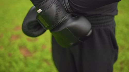 Black Boxing Gloves Closeup Outdoor Athlete Adjusts Wrist Straps Focused Warmup Grassy Park Poised