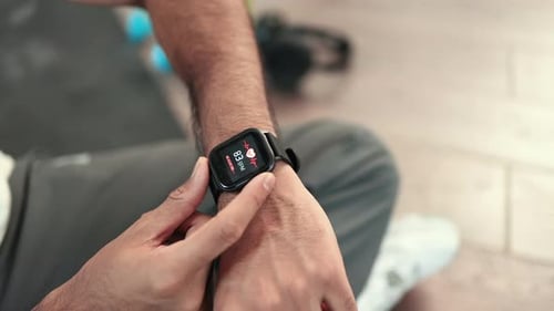Sporty Man Checking Pulse on Smartwatch After Workout Inside