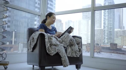 Woman Relaxing with Tablet in City Apartment