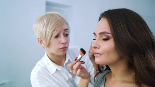 Makeup Artist Applying Powder to Beautiful Woman