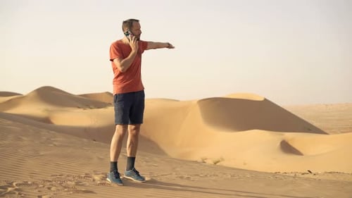 Angry, Lost Man Talking on Cellphone Walking on Desert 30s