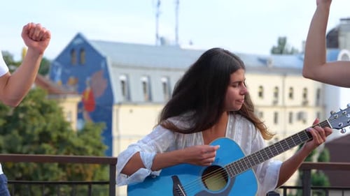 Young Adults Enjoying Rooftop Party with Guitar Music