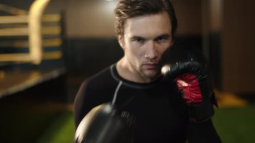 Portrait Of Angry Sport Man Practicing Boxing Punches In Fitness Center. Agitated Male Boxer Trai...