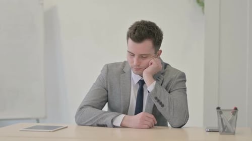 Joven empresario durmiendo sentado en el trabajo