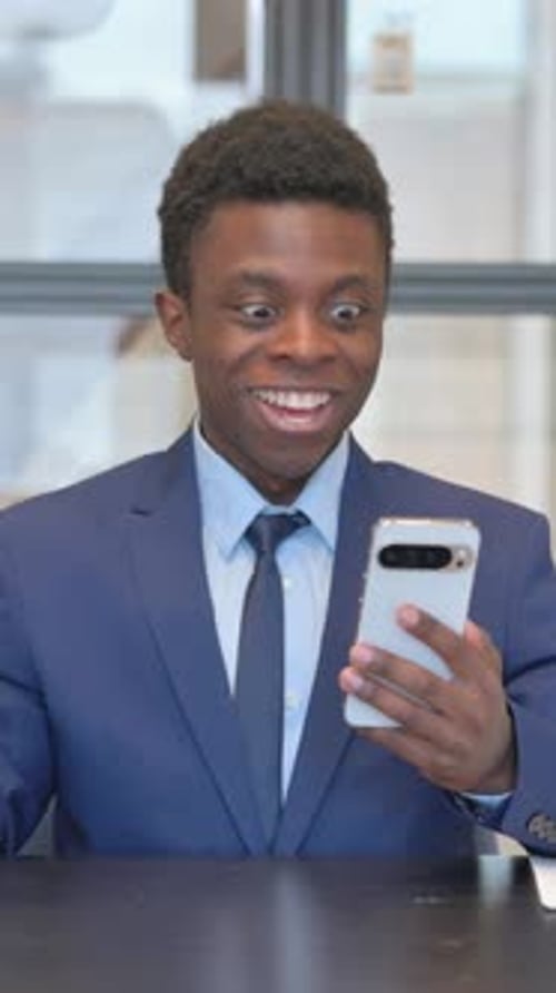 vertical video of African Businessman Celebrating Success on Phone in Office