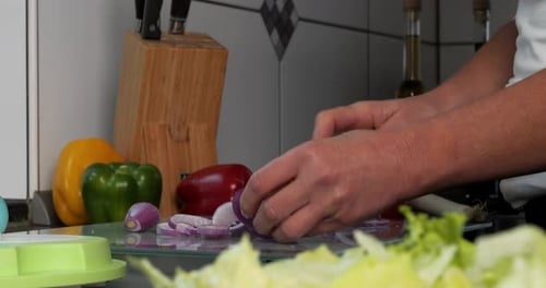 Close up of hands in a kitchen cutting an onion into onion rings