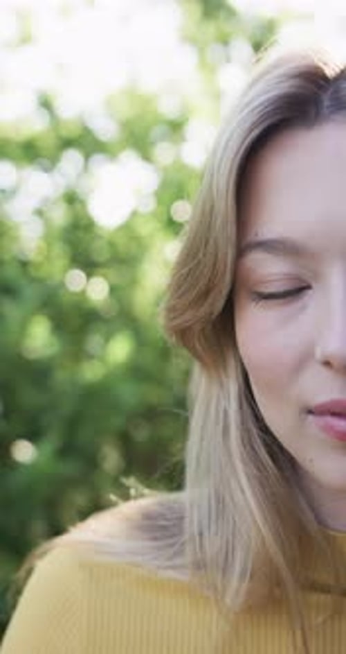 Vertical video of portrait of happy biracial woman smiling in garden, slow motion