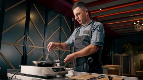 chef grilling beef patty with garlic and rosemary for burger in professional kitchen of restaurant