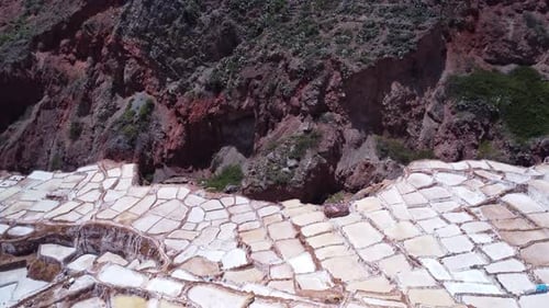 Salt Mines of Maras in the Sacred Valley of Peru, slow aerial dolly over drop off to rocks