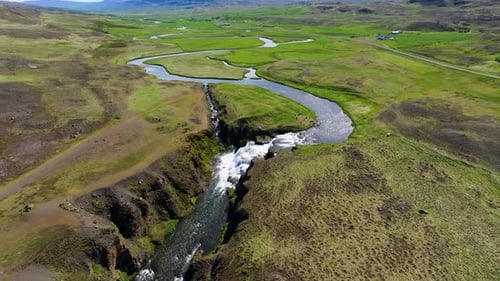 Aerial view of waterfall and river in lush mountains, Iceland.