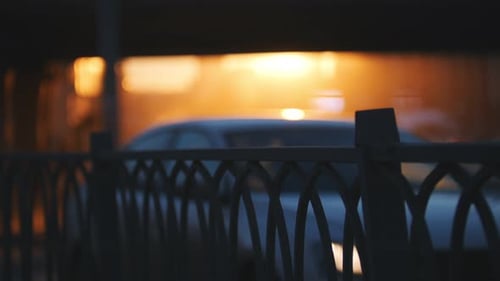 A Fence in Focus Cars Riding on the Road on