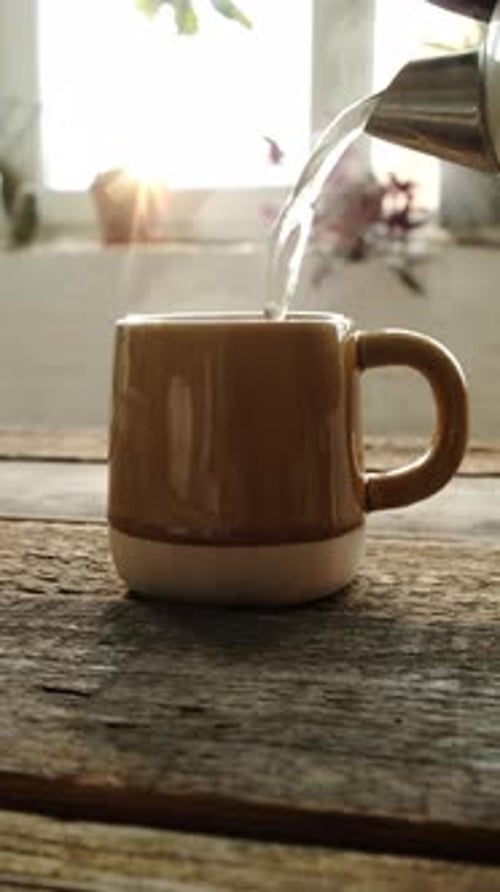 Pouring Hot Water Into Tea Cup in Kitchen