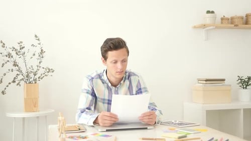 Young Man Reading Documents in Office