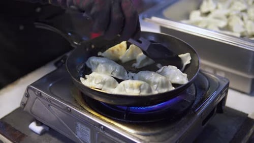 Street vendor is frying jiaozi in a pan
