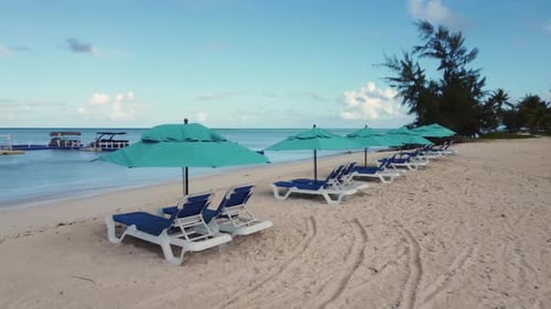 Orbit shot of beach chairs and umbrellas during a bright morning
