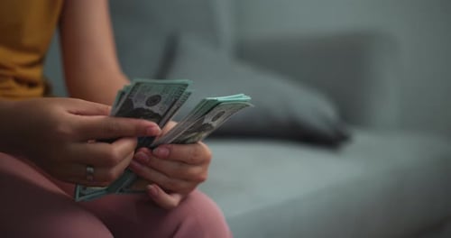 Close up hands of young asian women counting dollars banknotes at home.