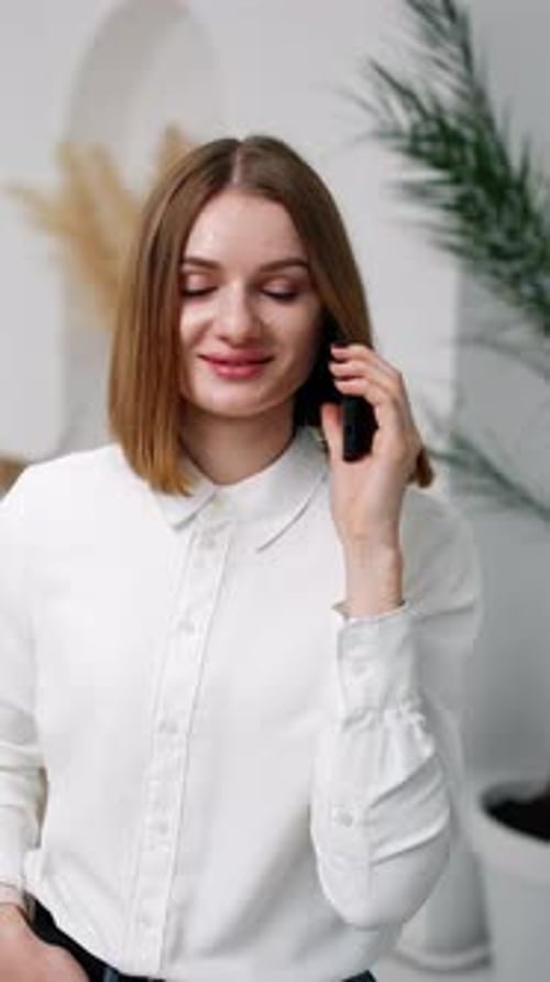 Smiling Woman in Blouse Talking on Phone Indoors