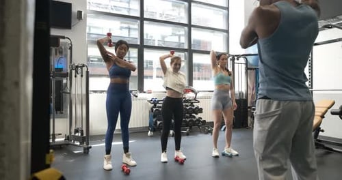 Group of Multiracial People Lifting Dumbbells in Fitness Studio Together