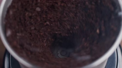 Fine coffee beans grinding. Close up on coffee grinding chamber.