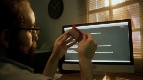 Bärtiger Mann untersucht und spielt mit roter Diskette am Schreibtisch herum