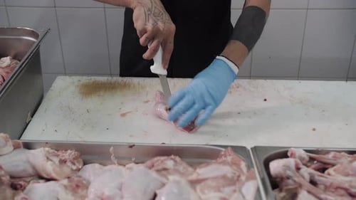 Metzger bereitet Hühnchenstücke auf einem Schneidebrett zu