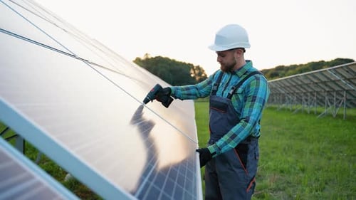 Male Technician Installing Solar Panels at Sunset