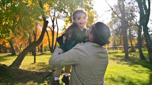 Glückliche Familie in einem Herbstpark. Vater nahm seine Tochter in die Arme und küsste sie. Zeitlupe