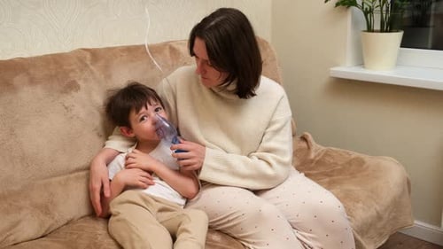 Caring Woman Helping Child Use Nebulizer at Home