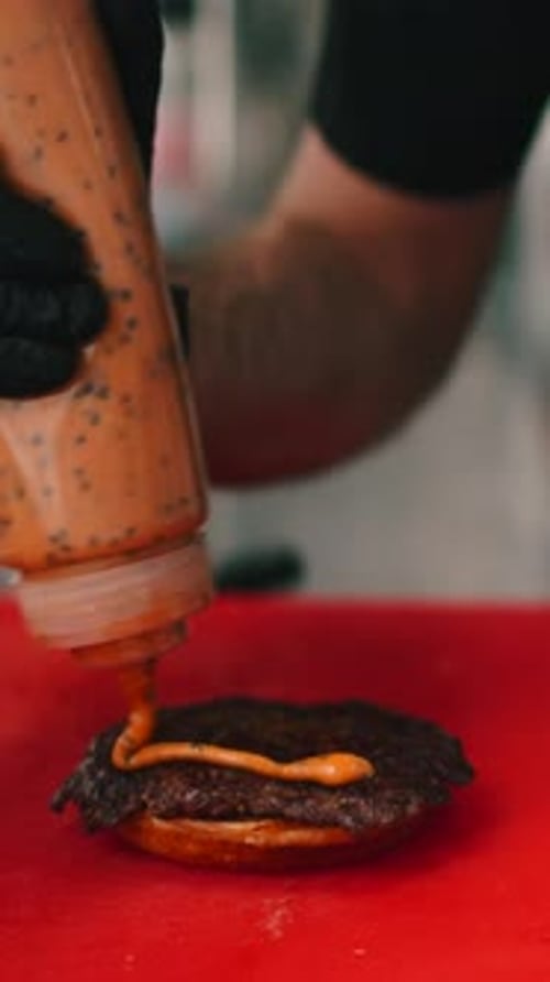 Chef Preparing Burger Squeezing Sauce on Patty