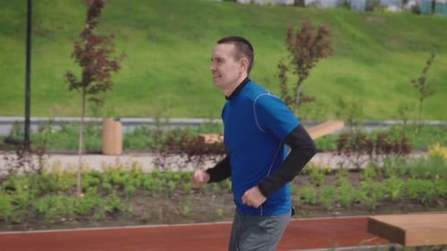 A Successful and Selfconfident Young Man Runs Through a Beautiful and Wellmaintained City Park