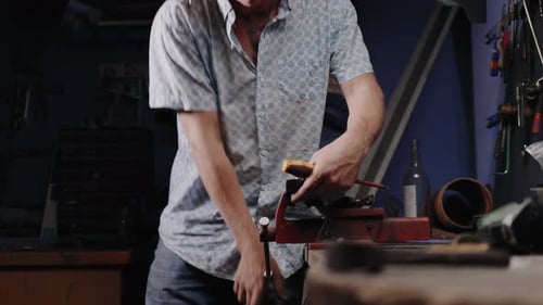 Cinematic shot of mechanic removing a bolt from a vice in his garage