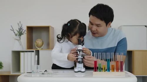Child and Man Studying Specimens with Microscope at Home