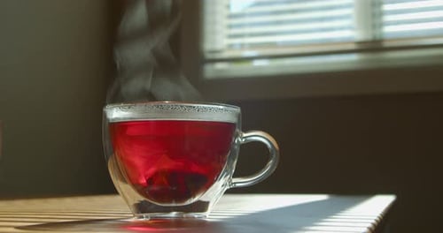 Tasse frisch gebrühten Schwarztee auf dem Küchentisch, Dampf, der warm ausstrahlt