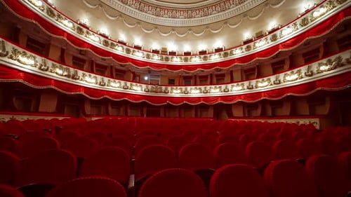 Classical theater inside. Rows of empty red velvet chairs in the opera house.