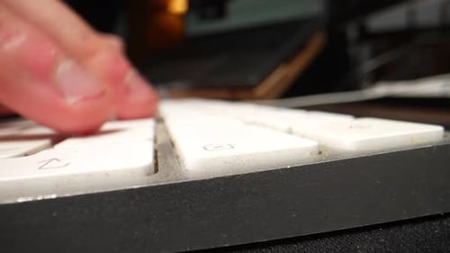 Un gros plan de doigts tapant sur un clavier blanc, puis appuyant à plusieurs reprises sur la touche Supprimer